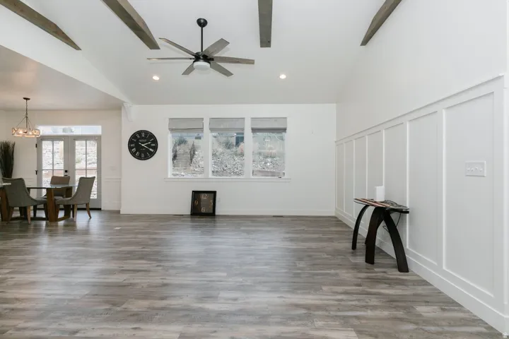 Living room with a decorative wall, light wood-type flooring, ceiling fan, wainscoting, and recessed lighting