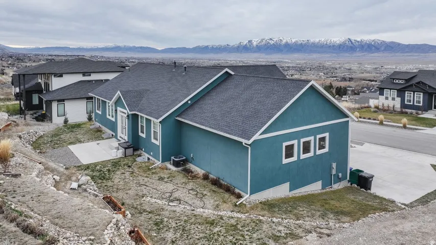 North side view of property exterior with a shingled roof, a mountain view, and stucco siding