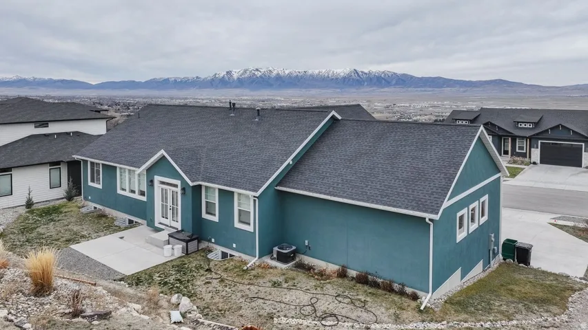View of front of house featuring a shingled roof, a mountain view, and stucco siding