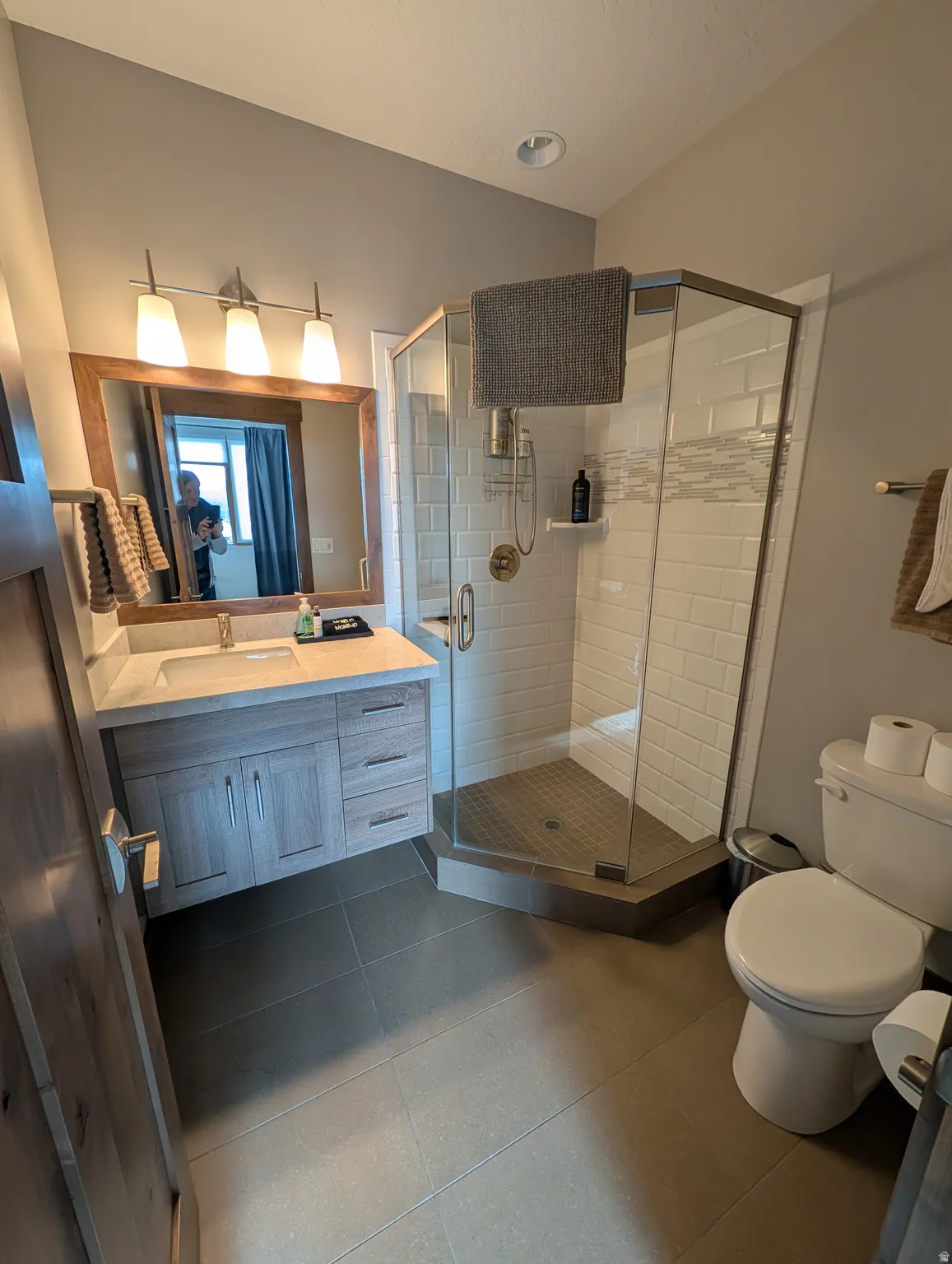 Full bath with vanity, a stall shower, and dark tile patterned flooring