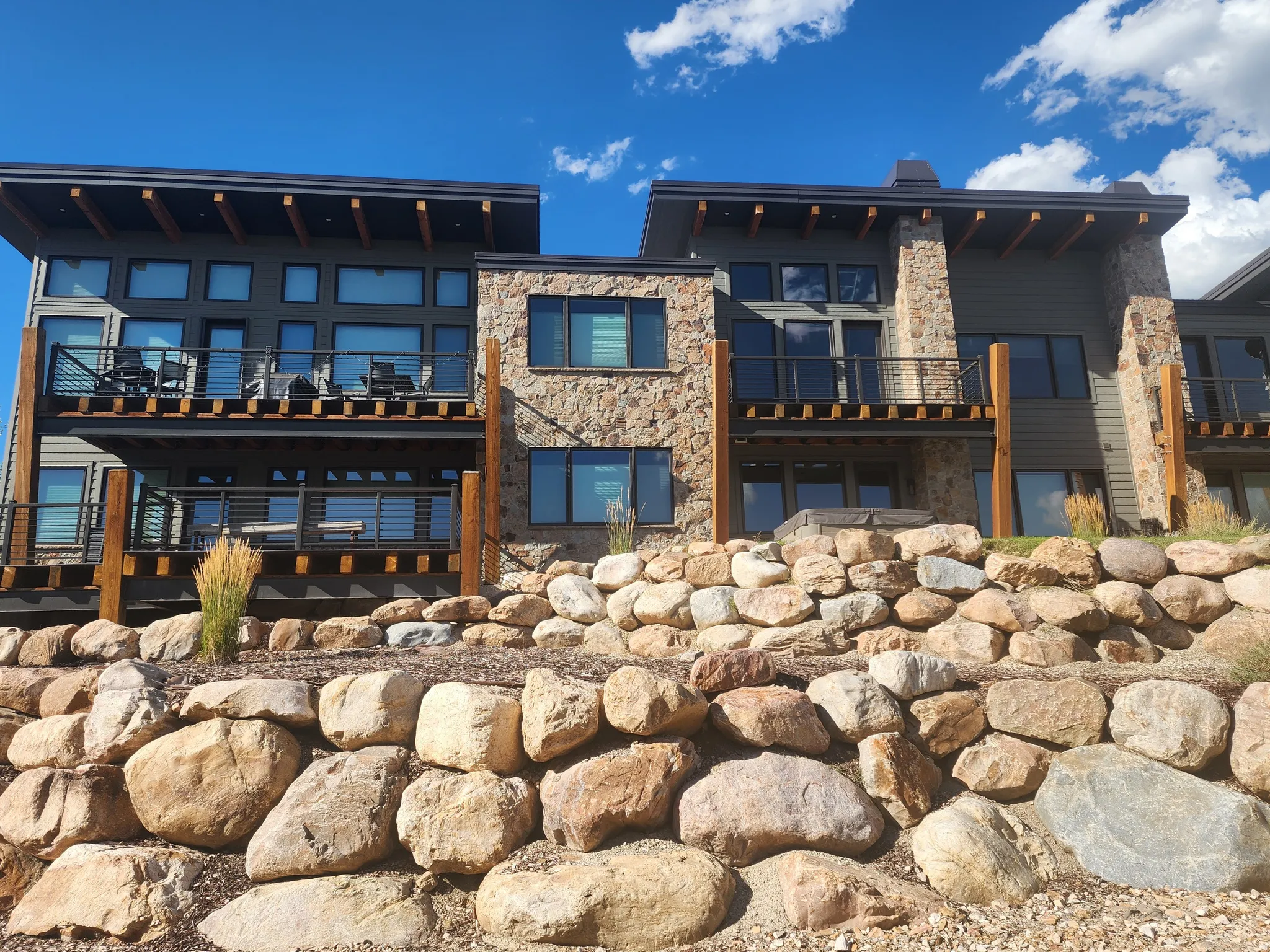 Rear view of property featuring stone siding, a balcony, and a chimney
