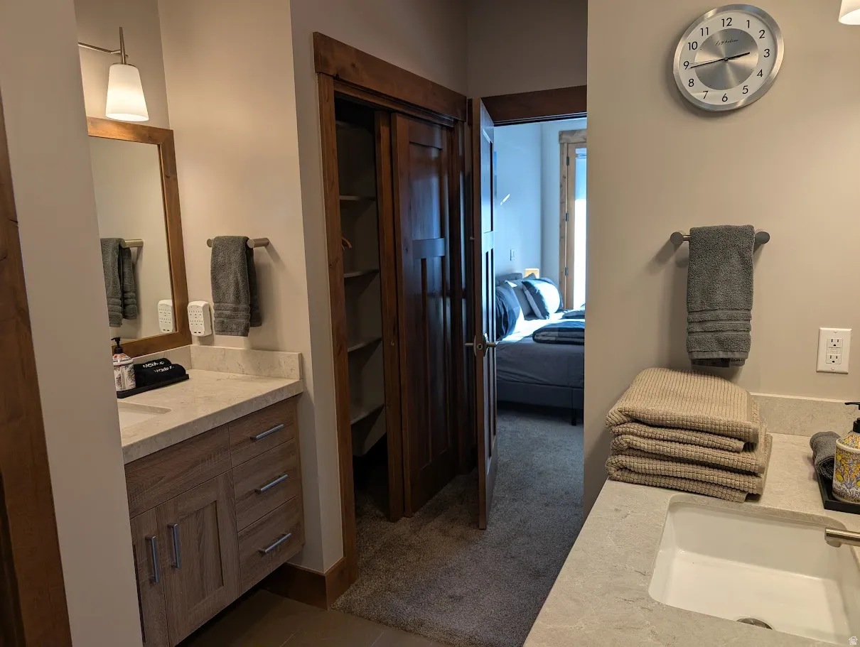 Full bath featuring two vanities, connected bathroom, and dark colored carpet