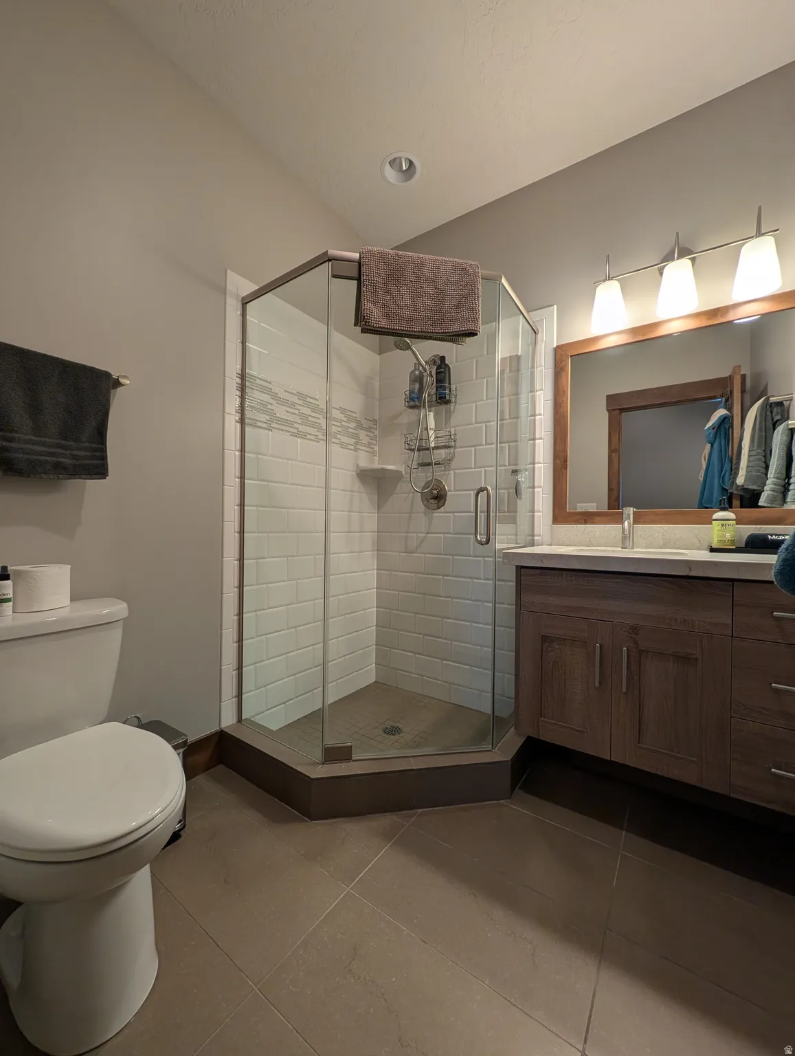 Full bath featuring vanity, dark tile patterned floors, and a stall shower