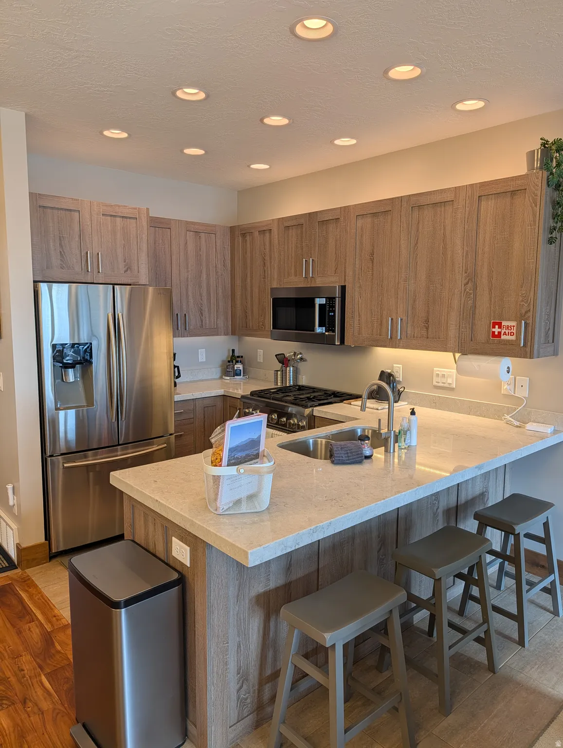 Kitchen featuring a breakfast bar, appliances with stainless steel finishes, light wood-type flooring, recessed lighting, and a textured ceiling