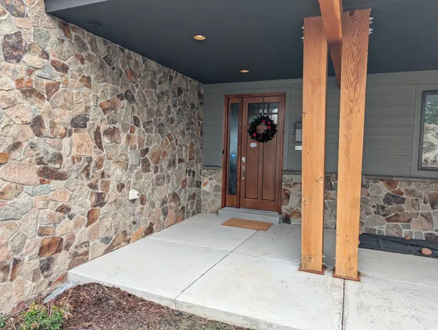 Doorway to property with stone siding and a porch