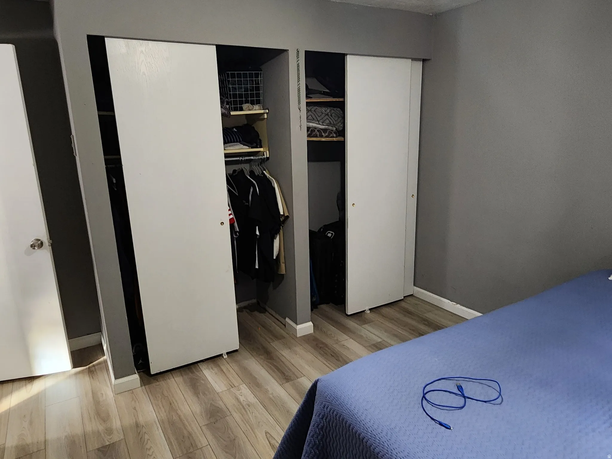 Bedroom with a textured ceiling, two closets, and light wood-style floors