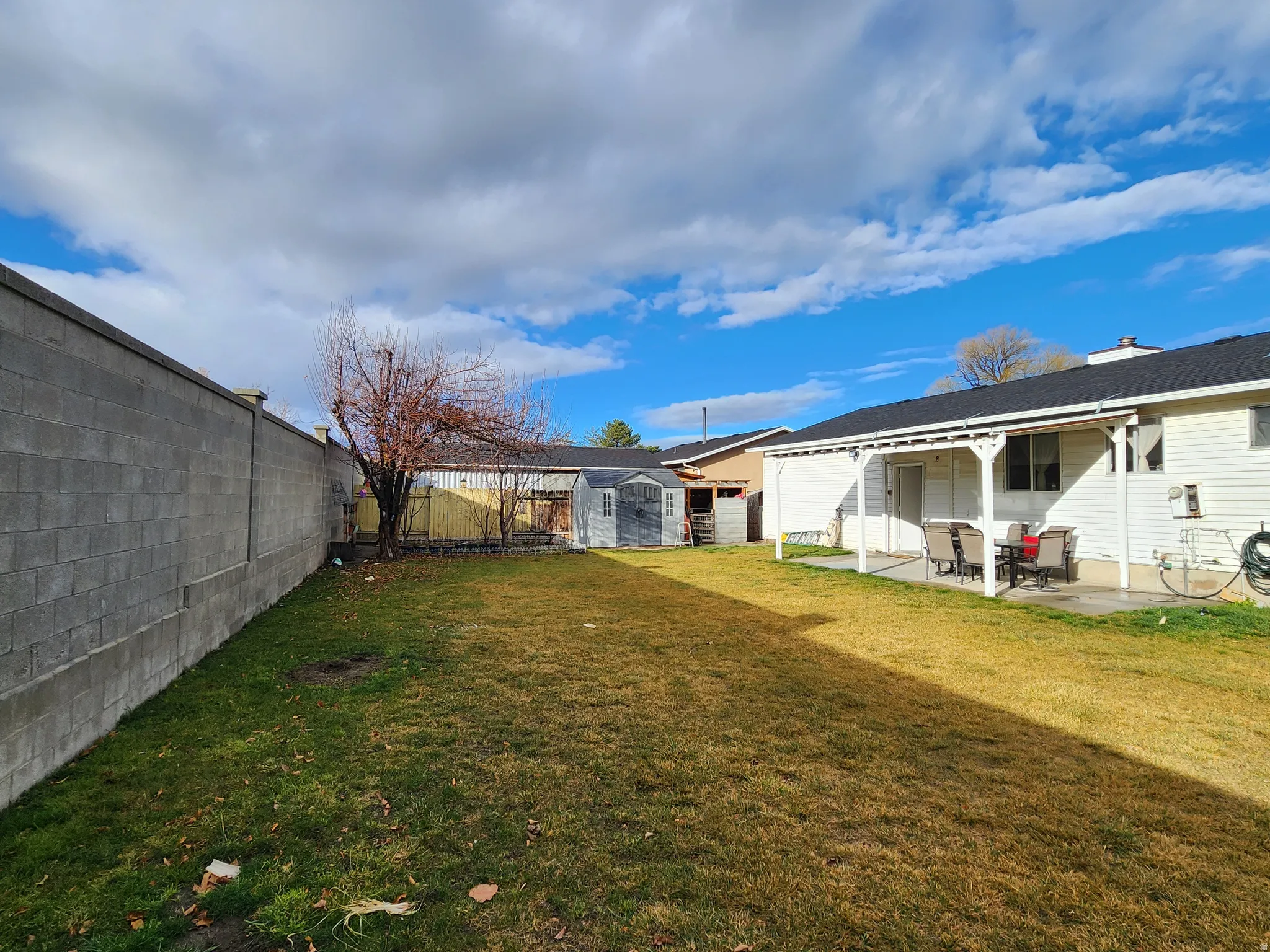 Fenced backyard featuring a shed and a patio