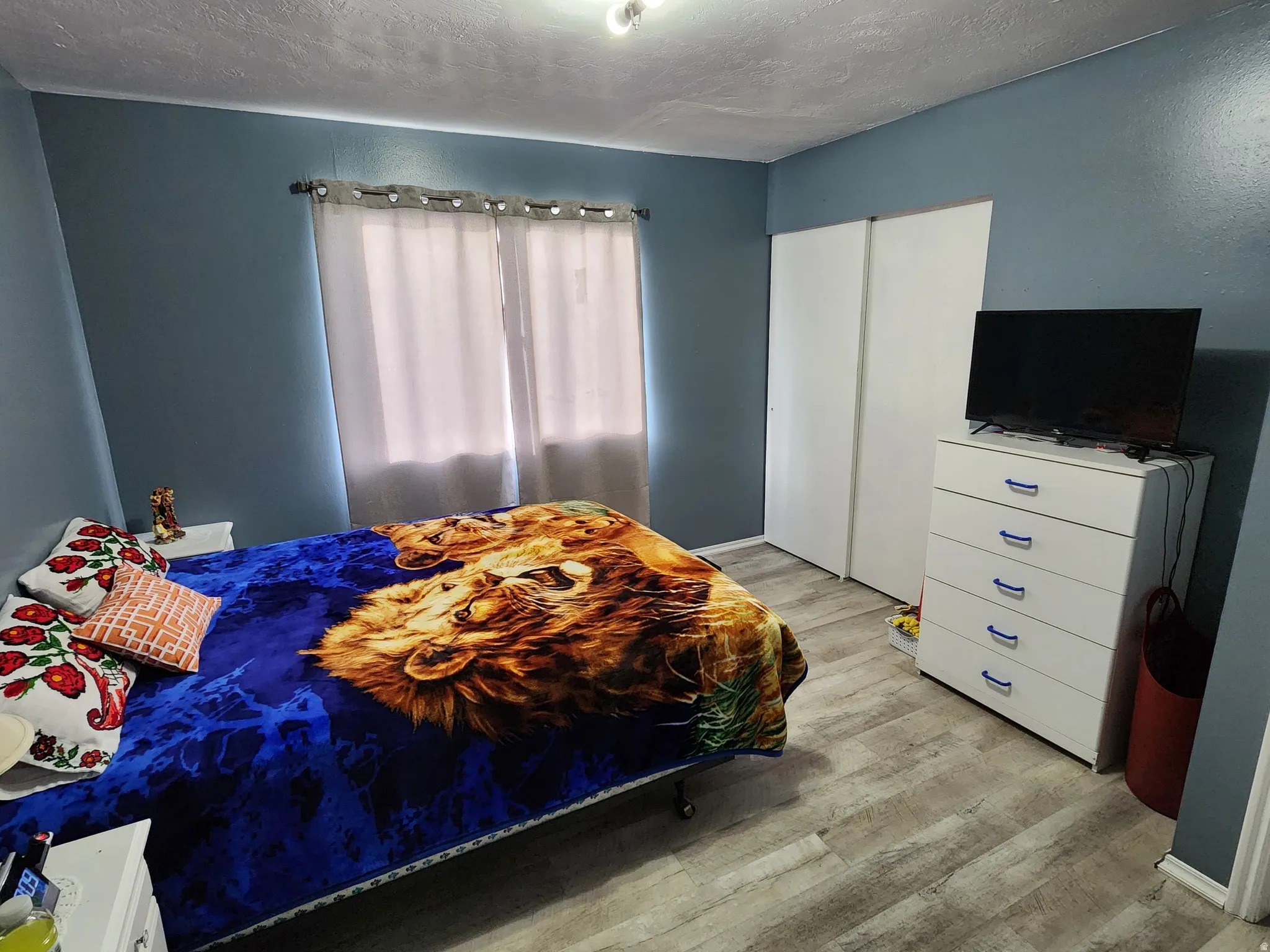 Bedroom with light wood-style floors, a textured ceiling, and a closet