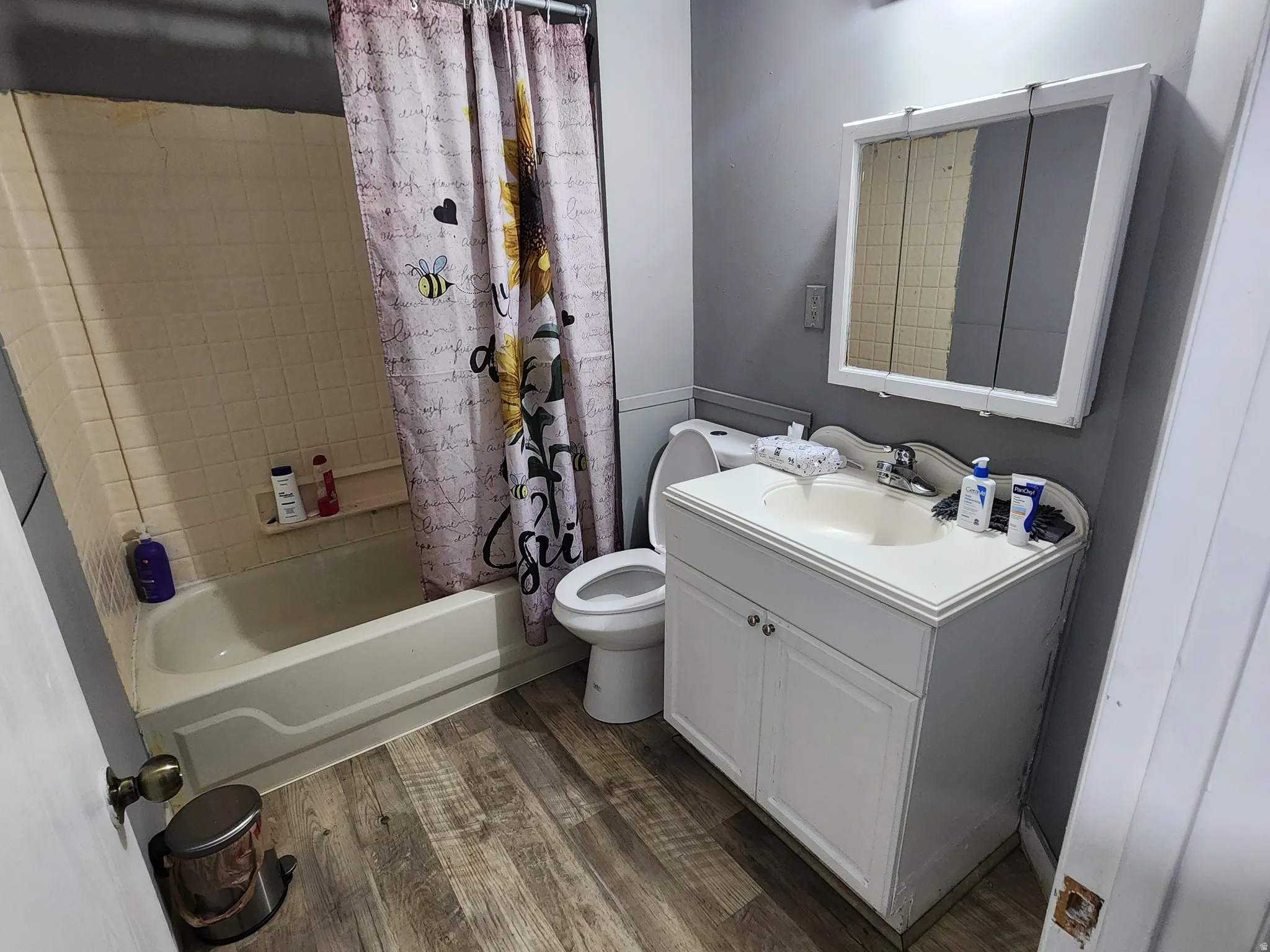 Bathroom with vanity, shower / tub combo with curtain, and dark wood-type flooring