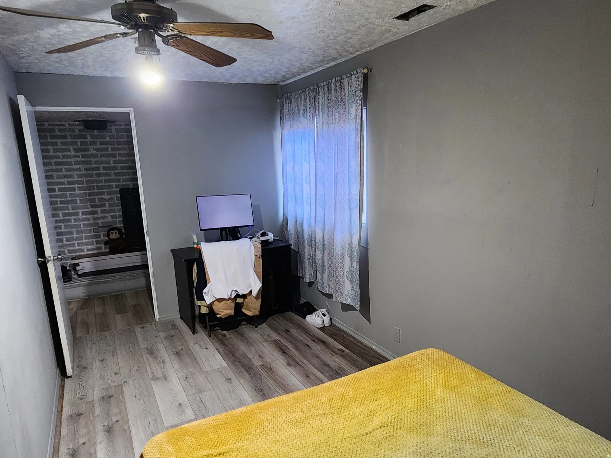 Bedroom with light wood-type flooring, a textured ceiling, and ceiling fan