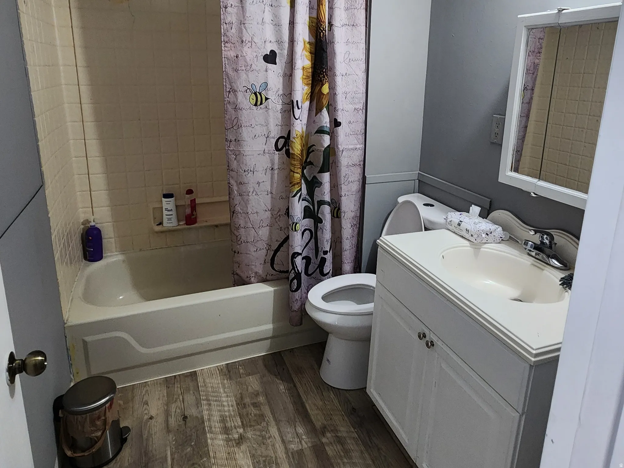 Bathroom with a textured ceiling, vanity, shower / tub combo with curtain, and dark wood finished floors