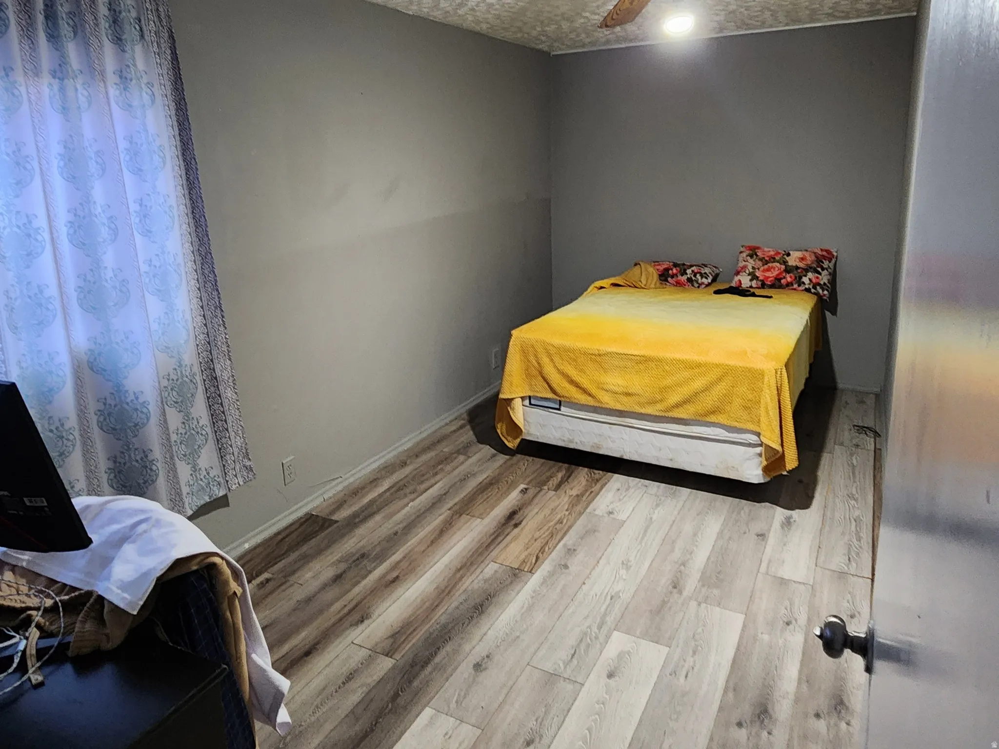 Bedroom with a textured ceiling, light wood-style floors, and ceiling fan