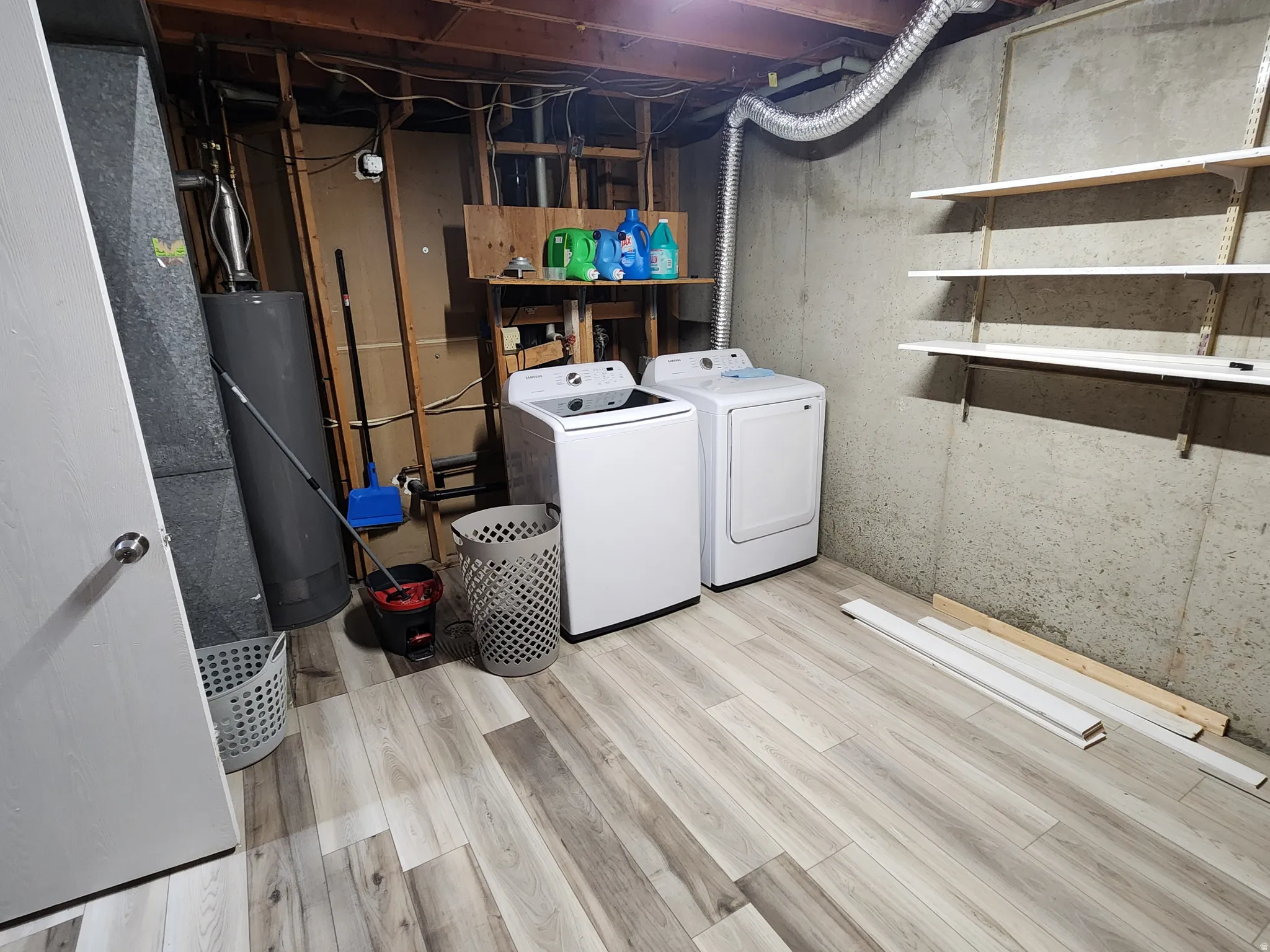 Laundry room featuring washer and clothes dryer, water heater, and wood finished floors