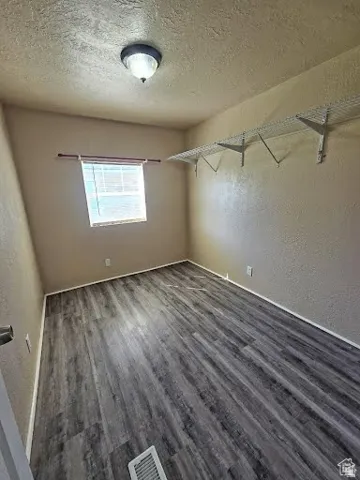 Spare room with a textured wall, a textured ceiling, and wood finished floors