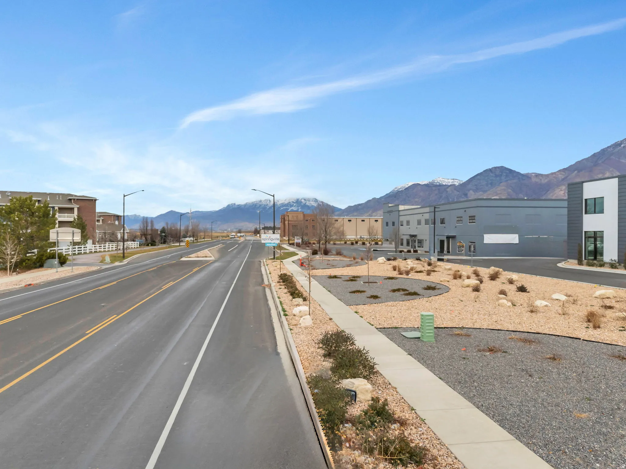 View of asphalt street with a mountain view, street lights, sidewalks, and curbs