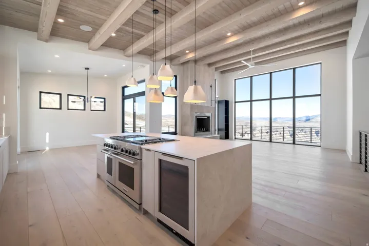 Kitchen with pendant lighting, double oven range, wine cooler, light wood-type flooring, and a wood ceiling with exposed beams