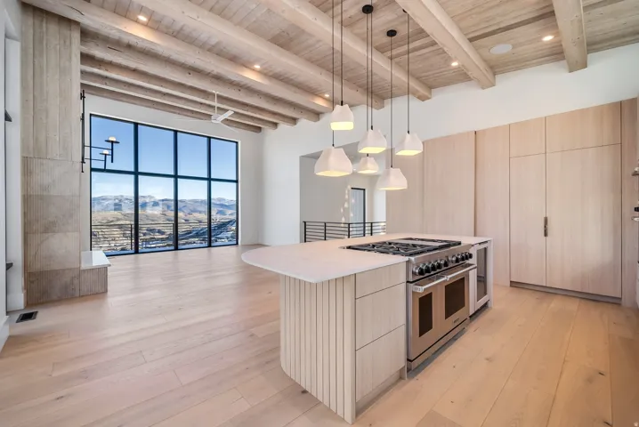 Kitchen with hanging light fixtures, range with two ovens, light wood-style flooring, a wooden ceiling with exposed beams, and modern cabinets