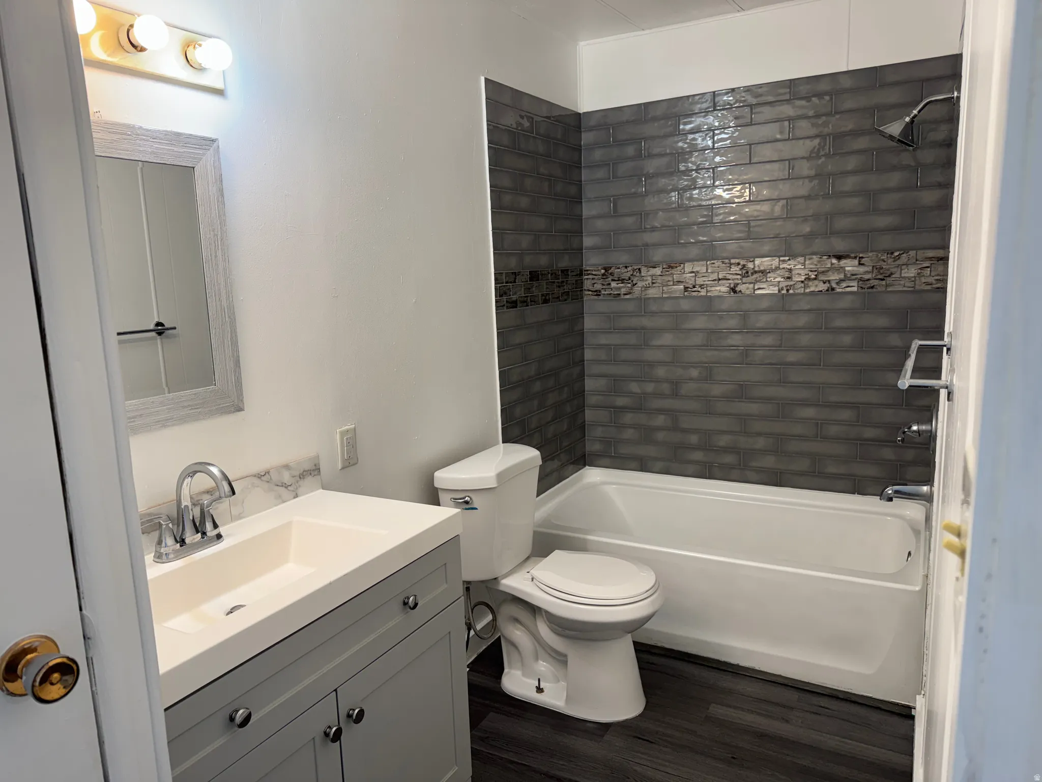 Bathroom with vanity, bathtub / shower combination, and dark wood-style flooring