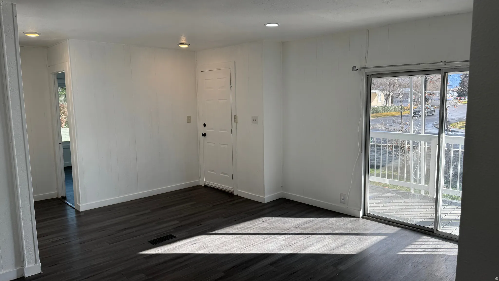 Empty room with dark wood-type flooring, healthy amount of natural light, and recessed lighting