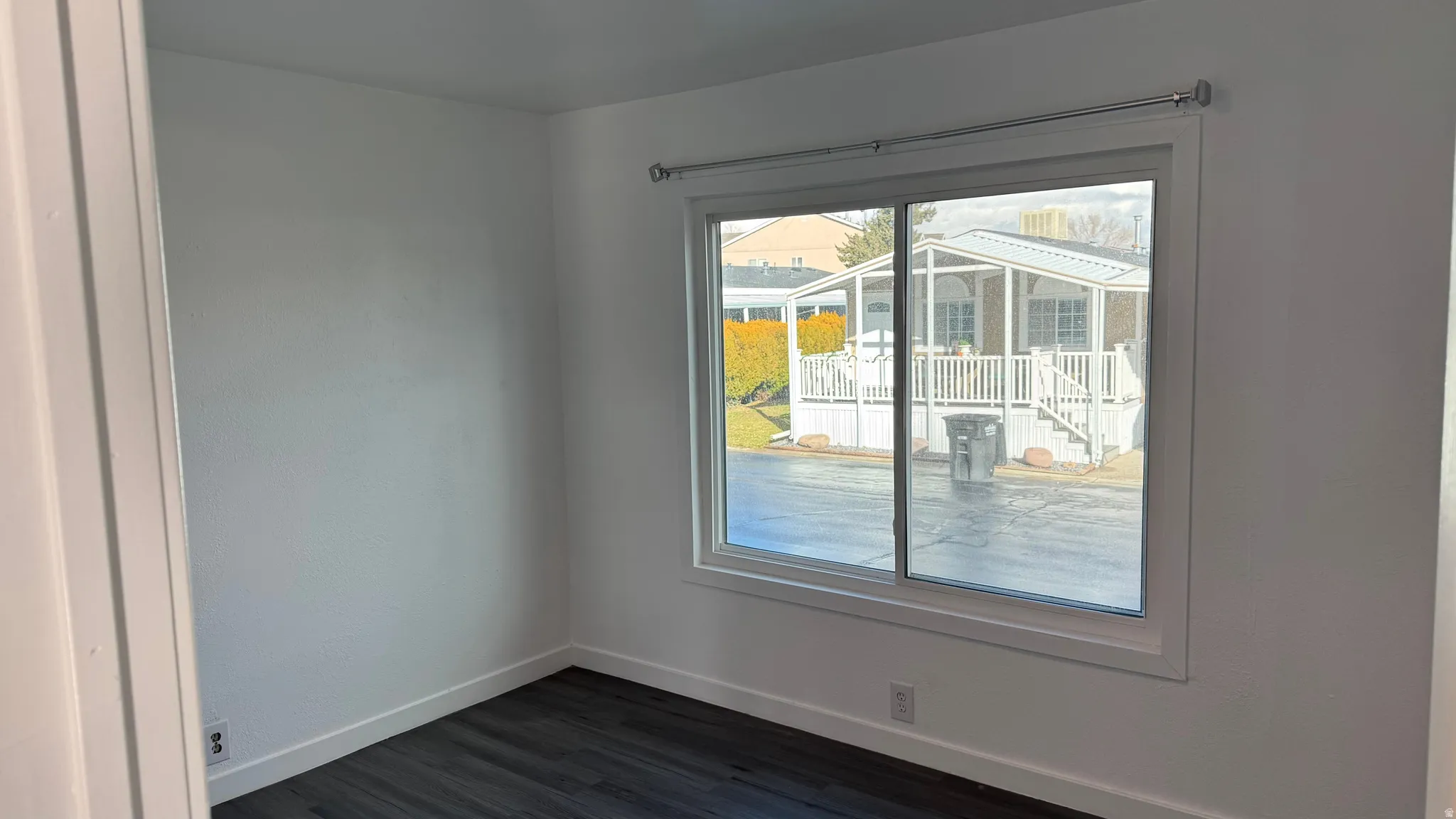Unfurnished room with baseboards and dark wood-type flooring