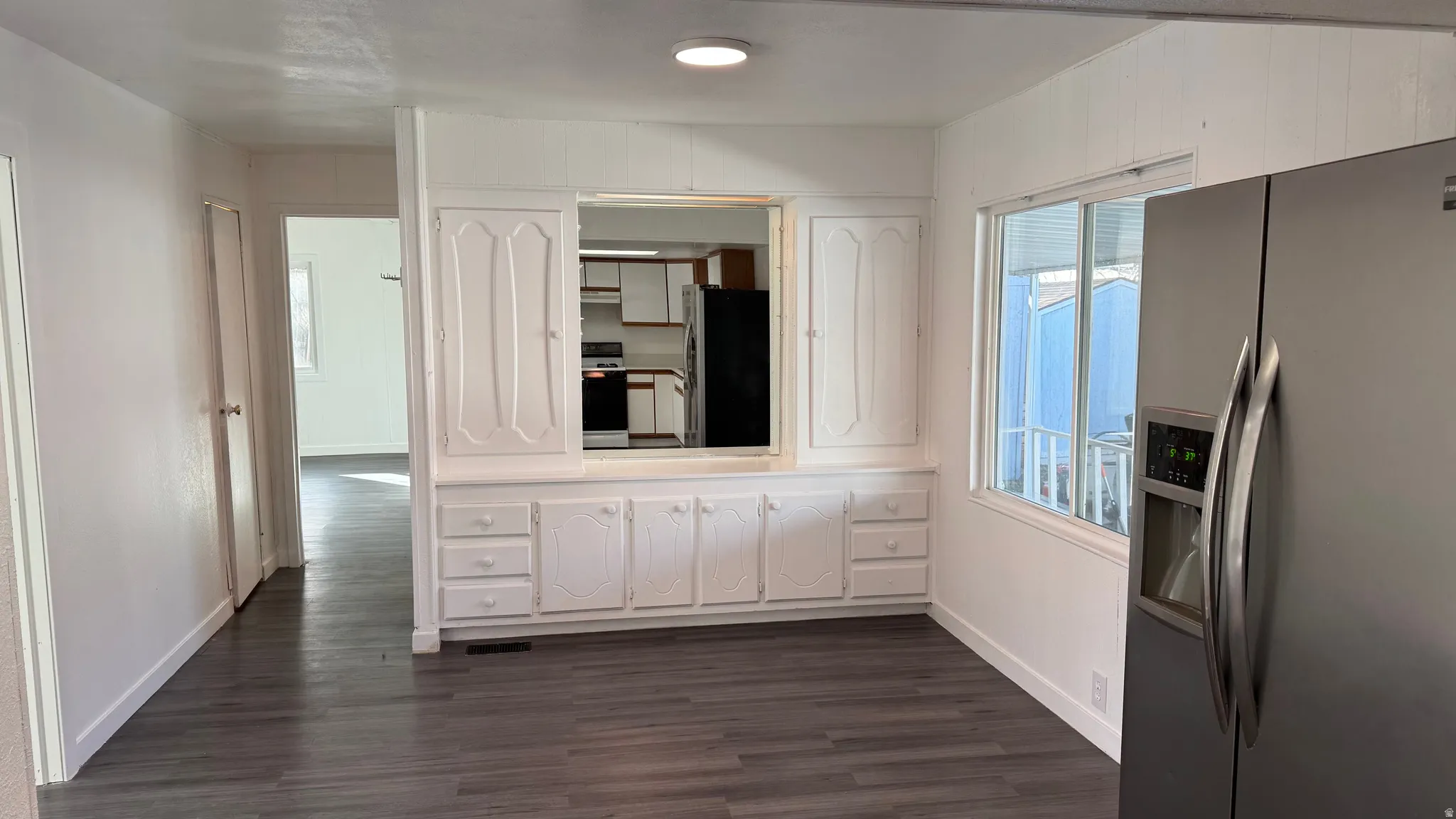 Unfurnished dining area featuring dark wood-type flooring and baseboards