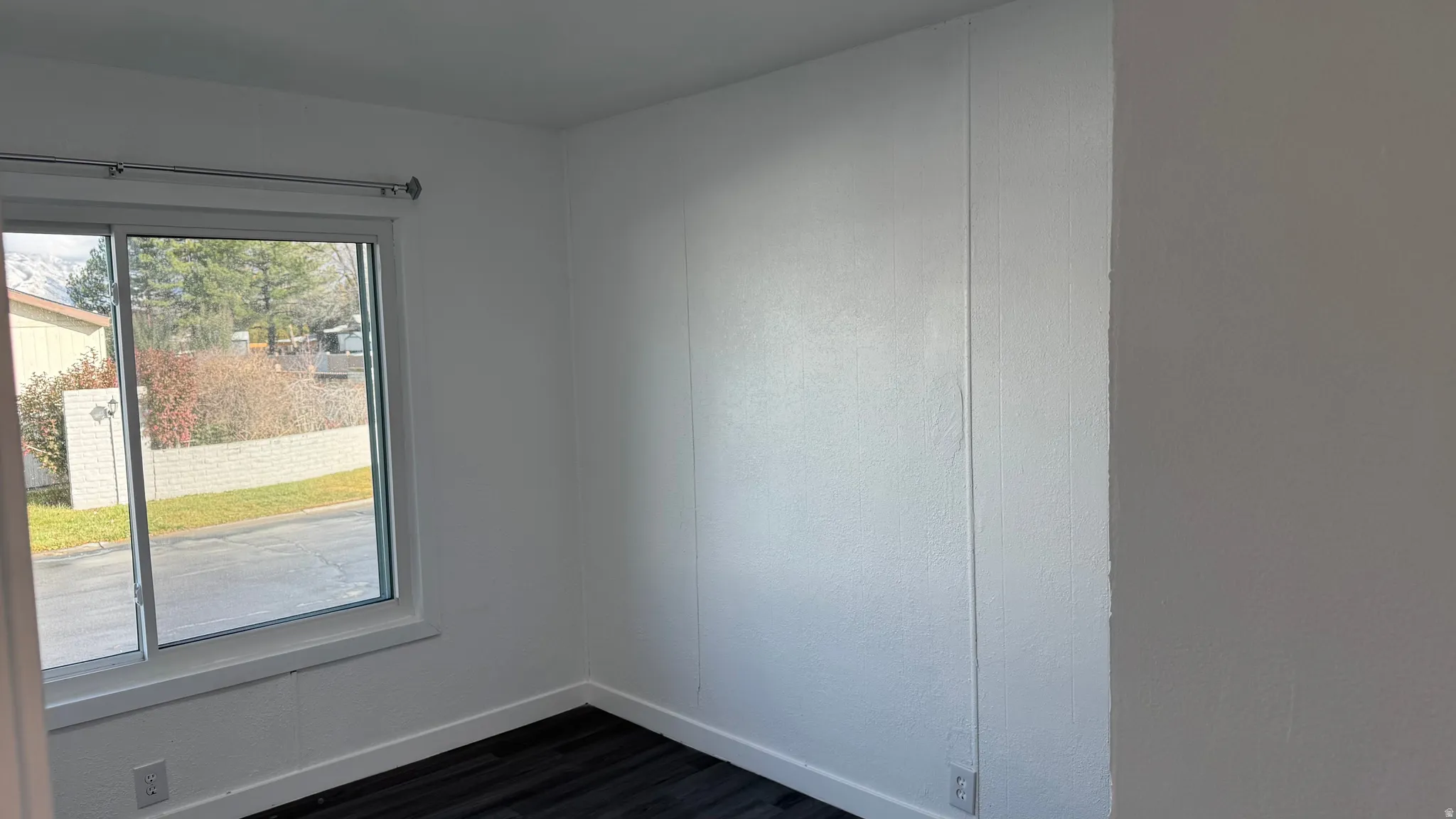 Unfurnished room with dark wood-type flooring and baseboards