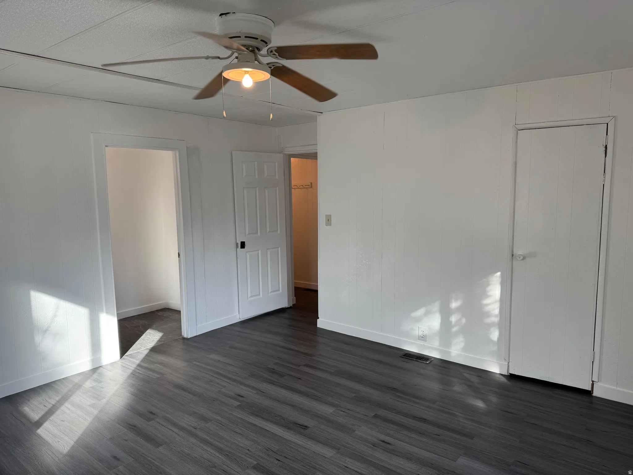 Unfurnished bedroom with dark wood-style flooring and ceiling fan