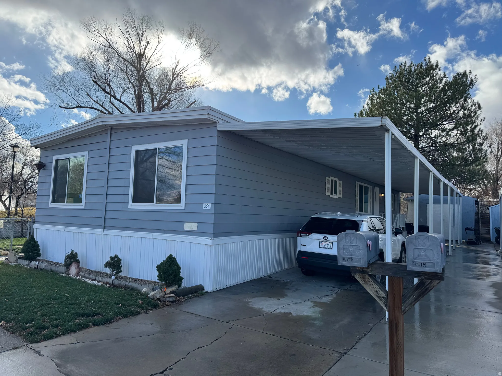 View of home's exterior featuring an attached carport, driveway, and a lawn