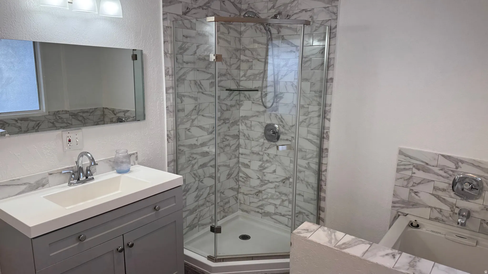 Full bath featuring a textured wall, a stall shower, vanity, and a garden tub