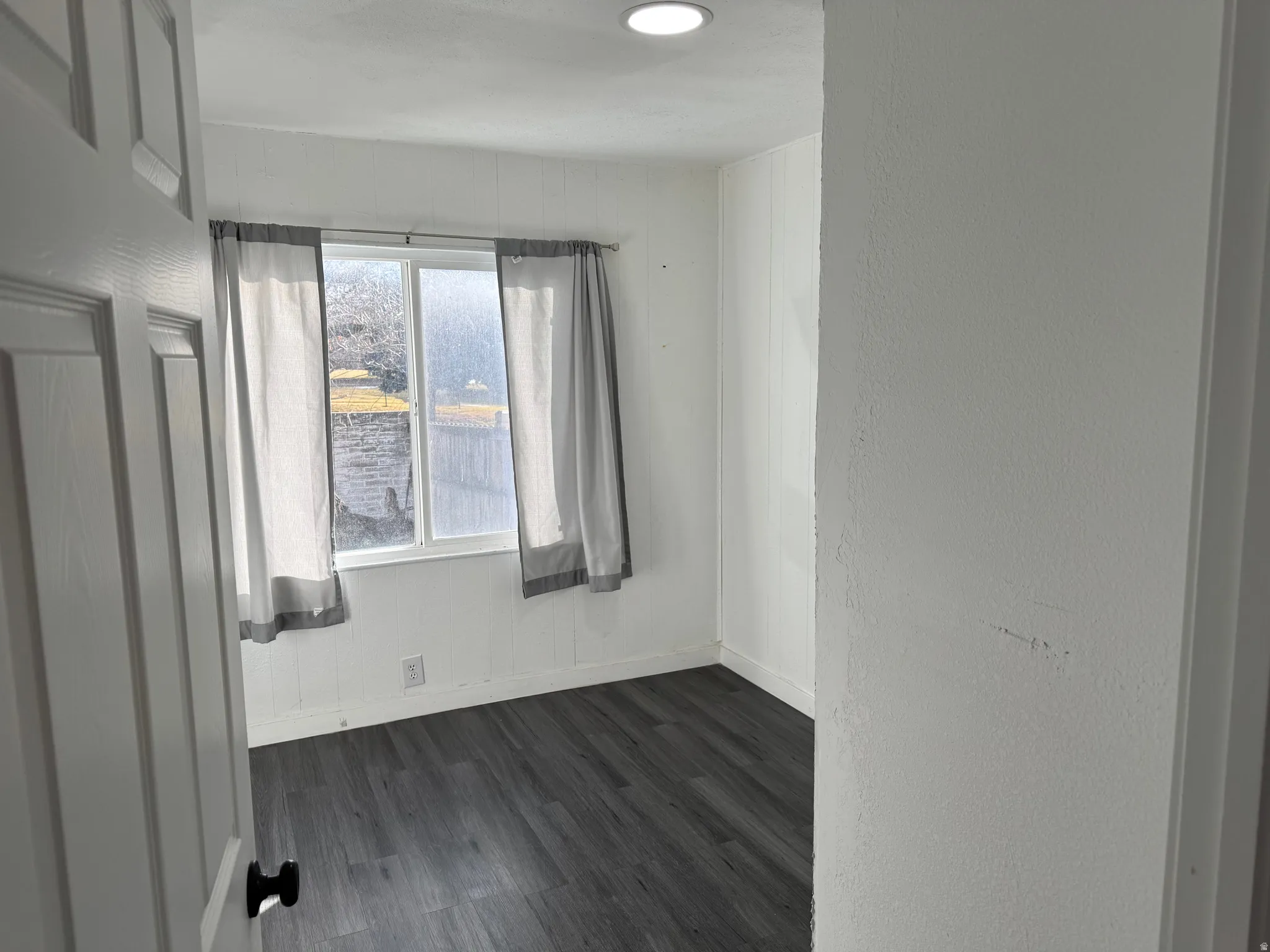 Unfurnished room featuring dark wood finished floors and a textured wall