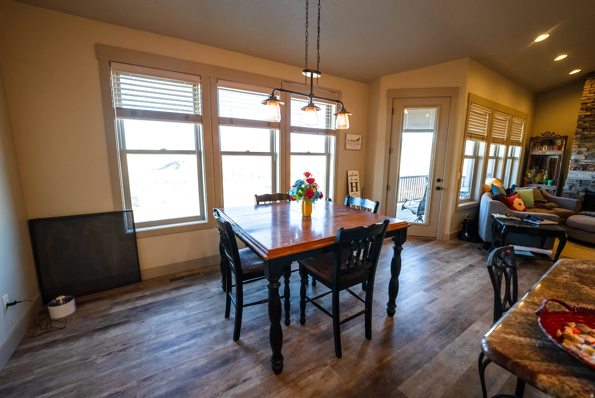 Dining area featuring dark wood-type flooring, vaulted ceiling, recessed lighting, and a stone fireplace