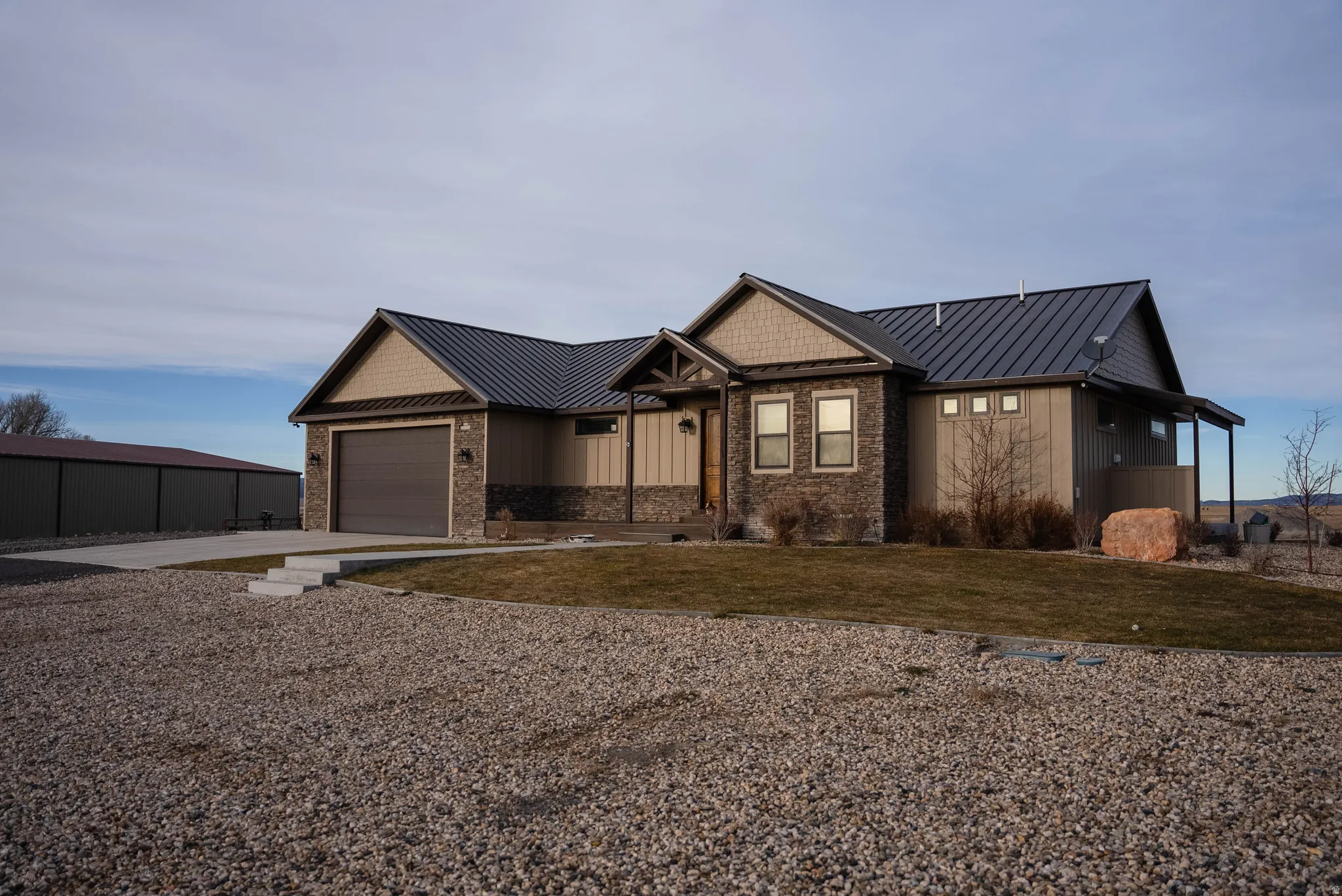 View of front of property featuring a standing seam roof, a metal roof, concrete driveway, a front yard, and a garage