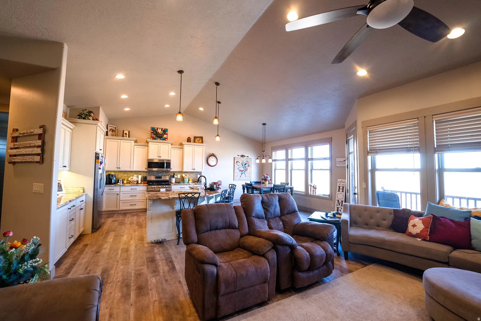 Living room featuring light wood-style floors, recessed lighting, ceiling fan, and high vaulted ceiling