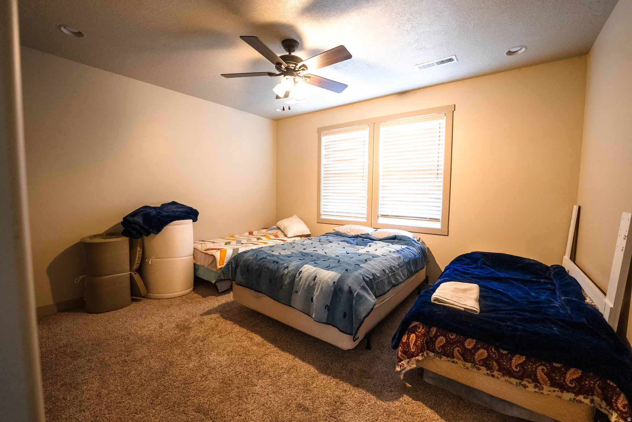 Carpeted bedroom with ceiling fan and a textured ceiling