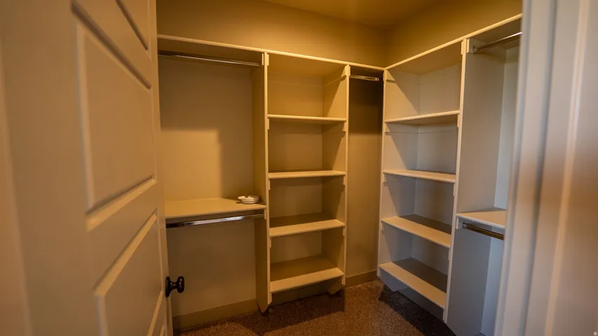 Walk-in closet featuring built-in shelving, multiple hanging rods, and neutral-toned carpeting