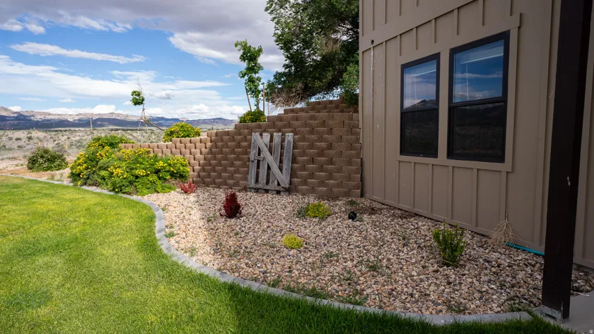 Exterior featuring tan board and batten siding, black framed windows, and a landscaped perimeter