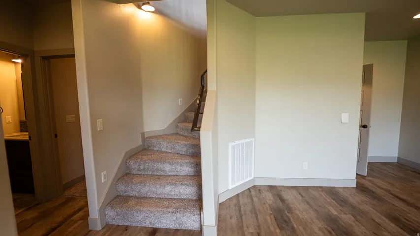 Carpeted staircase with recessed lighting, wood-finish flooring, and neutral wall tones