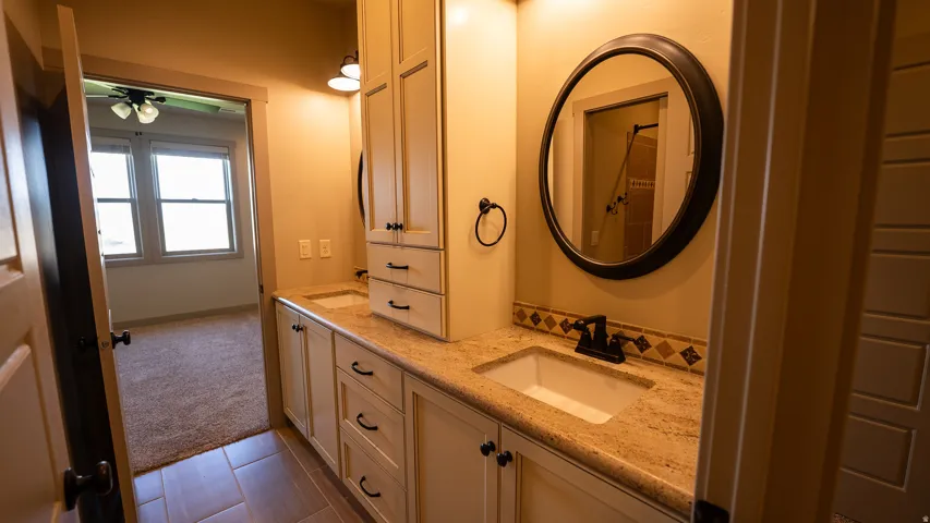 Double vanity bathroom featuring granite countertops and light-toned cabinetry