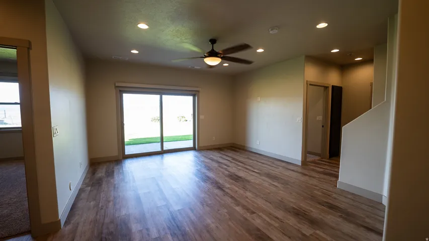 Spacious room featuring wood-finish flooring, a ceiling fan with integrated lighting, recessed lighting, and a large sliding glass door opening to an outdoor area