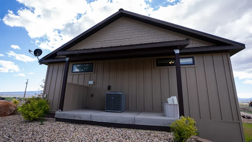 Exterior wall featuring board and batten siding with shake accents, a covered concrete patio, and a gravel landscape