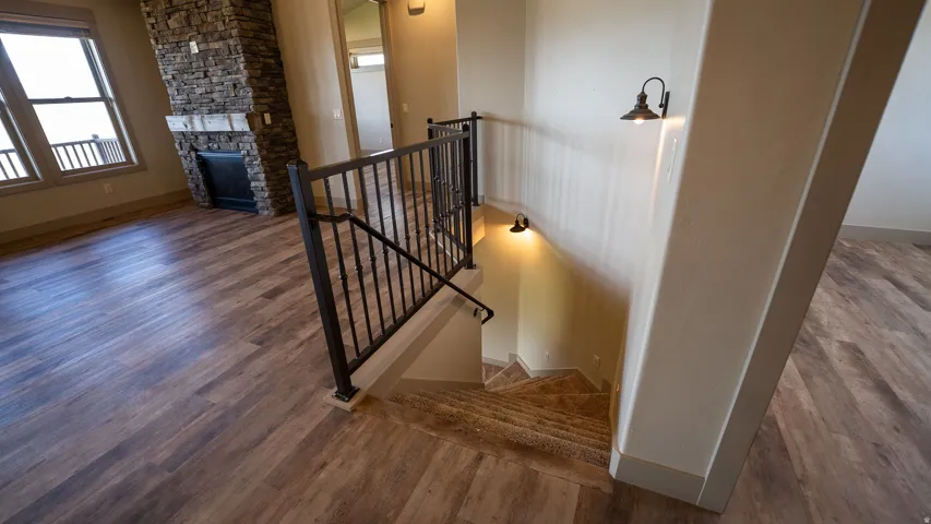 Spacious interior featuring wood-finish flooring, a stone-clad fireplace, and a black wrought iron staircase railing with decorative spindles