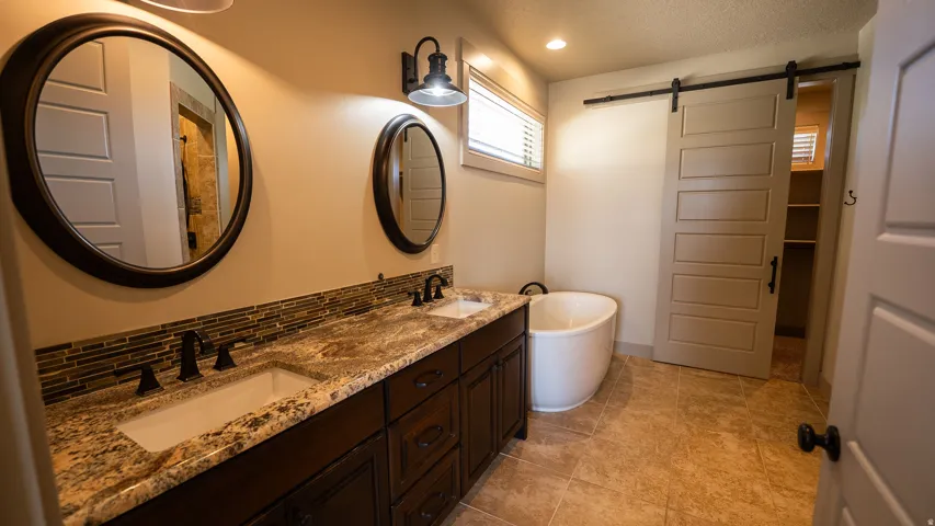 Double vanity featuring granite countertops, undermount sinks, and bronze fixtures