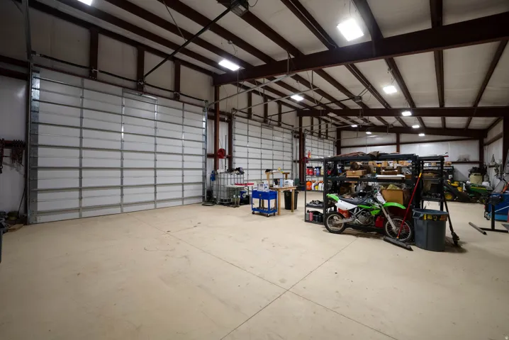 Spacious interior features multiple large garage doors, exposed beam ceiling, concrete flooring, and ample overhead lighting