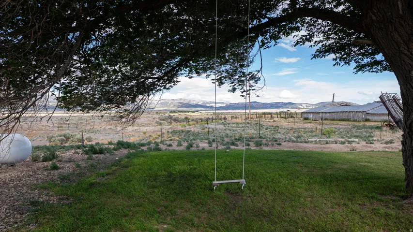 Sprawling outdoor area featuring a mature tree, a grassy lawn, and a distant mountain range
