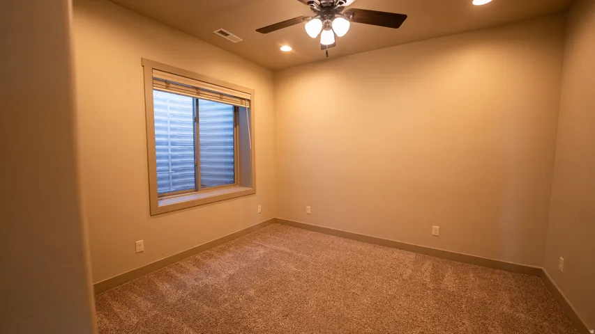 Carpeted room featuring a window with blinds, ceiling fan with integrated lighting, recessed lighting, and neutral wall tones