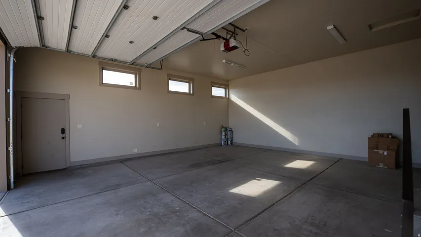 Spacious garage with a concrete floor, two upper windows, and a side access door