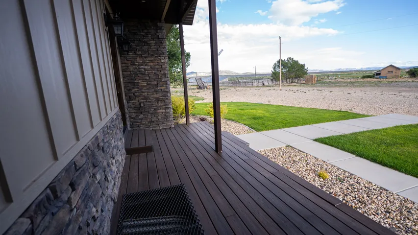 Inviting front porch featuring dark wood-finish decking, a stone veneer facade, and board and batten siding