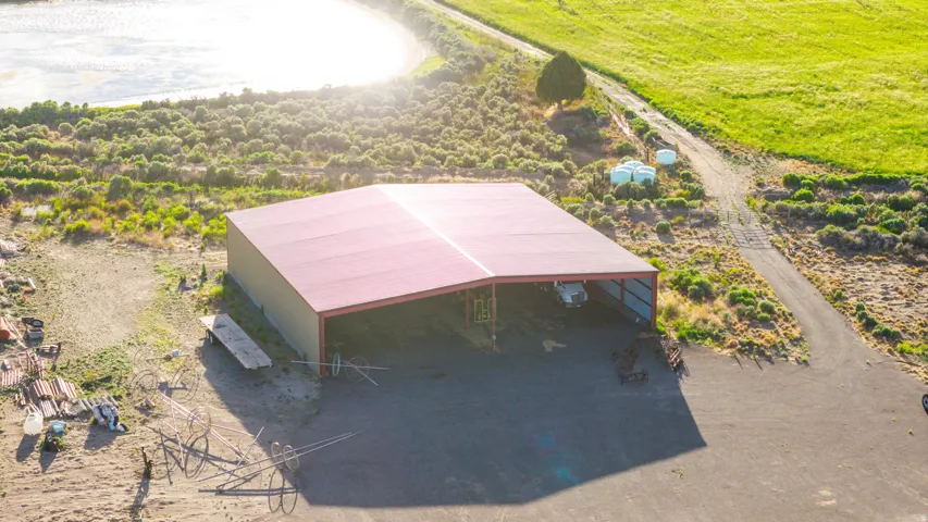 Spacious red-roofed pole barn with an open-sided design and an expansive gravel apron