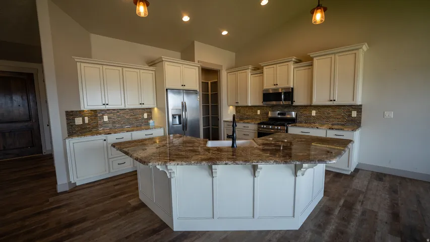 Gourmet kitchen featuring a large central island with seating, a deep single-basin sink with a matte black faucet, and ample cabinetry with varied storage options