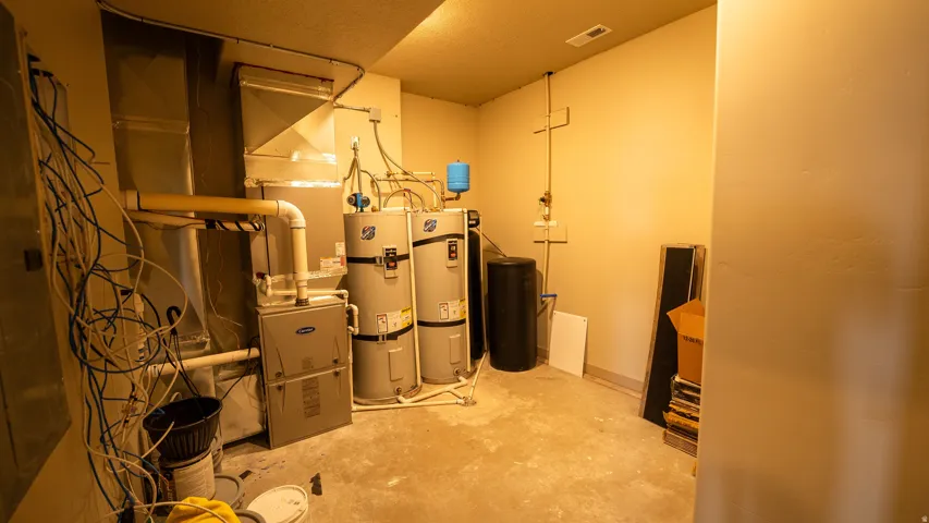 Utility room featuring two water heaters, a furnace, air handler, and exposed ductwork